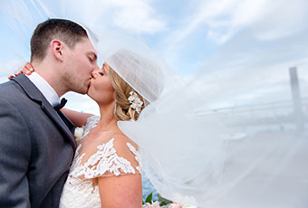 Bride and groom kiss under a blue sky at Kimpton Riverplace Hotel