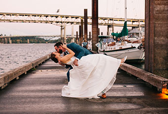 groom dips bride and kisses her down by the boats