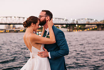groom kisses brides forehead down by the water