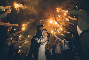 newlyweds kiss as wedding guests hold up sparklers